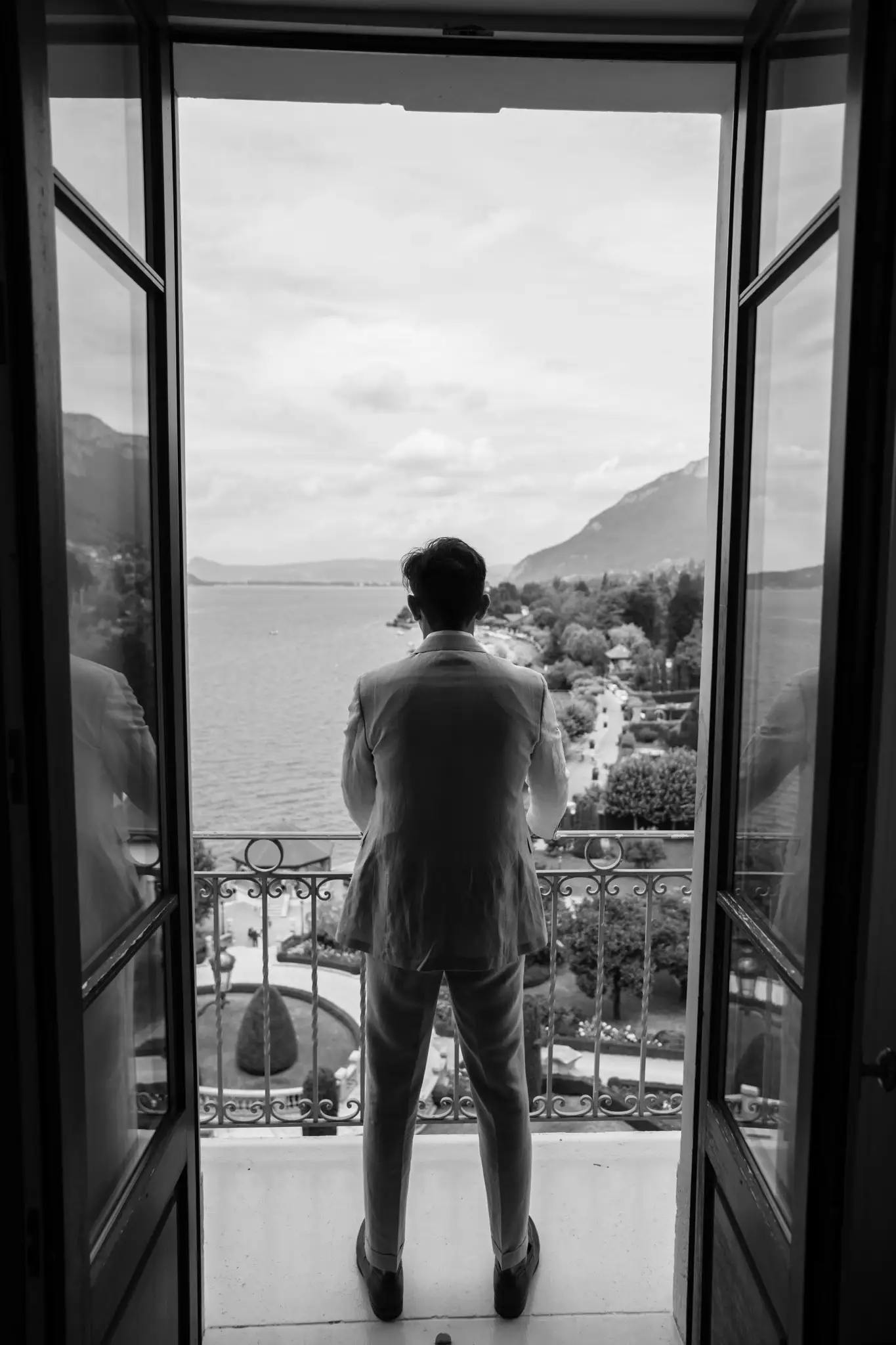 Le marié regarde la vue sur le lac d'Annecy du balcon du Palace de Menthon en juillet