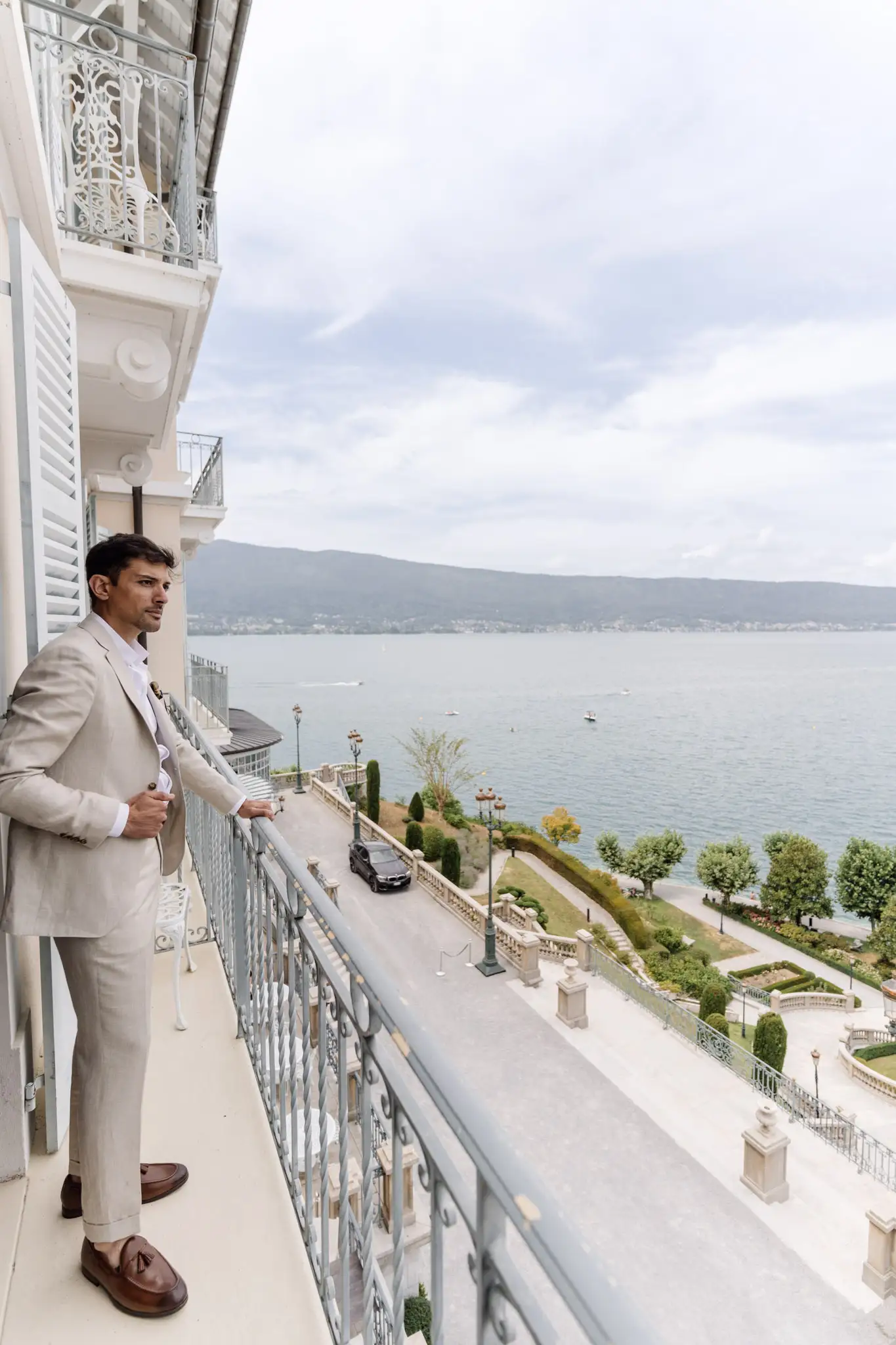 Le marié regarde la vue sur le lac d'Annecy du balcon du Palace de Menthon
